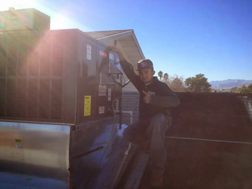 HVAC technician performing Air Duct Cleaning on a rooftop unit in Melrose